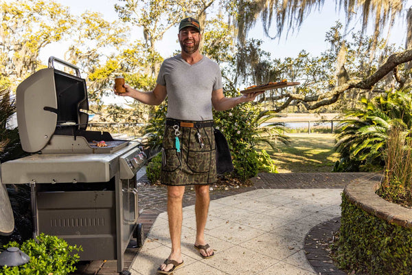 Grilling happy person with tools and pretty backyard with food and grilling apron