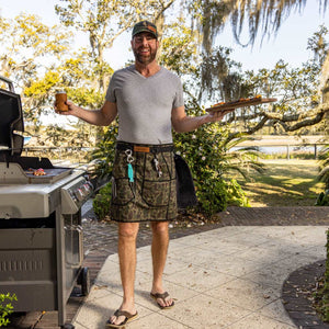 Grilling happy person with tools and pretty backyard with food and grilling apron