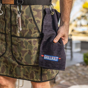 man with grillkilt towel in hand and lots of grilling accessories. grillkilt the ultimate grilling apron
